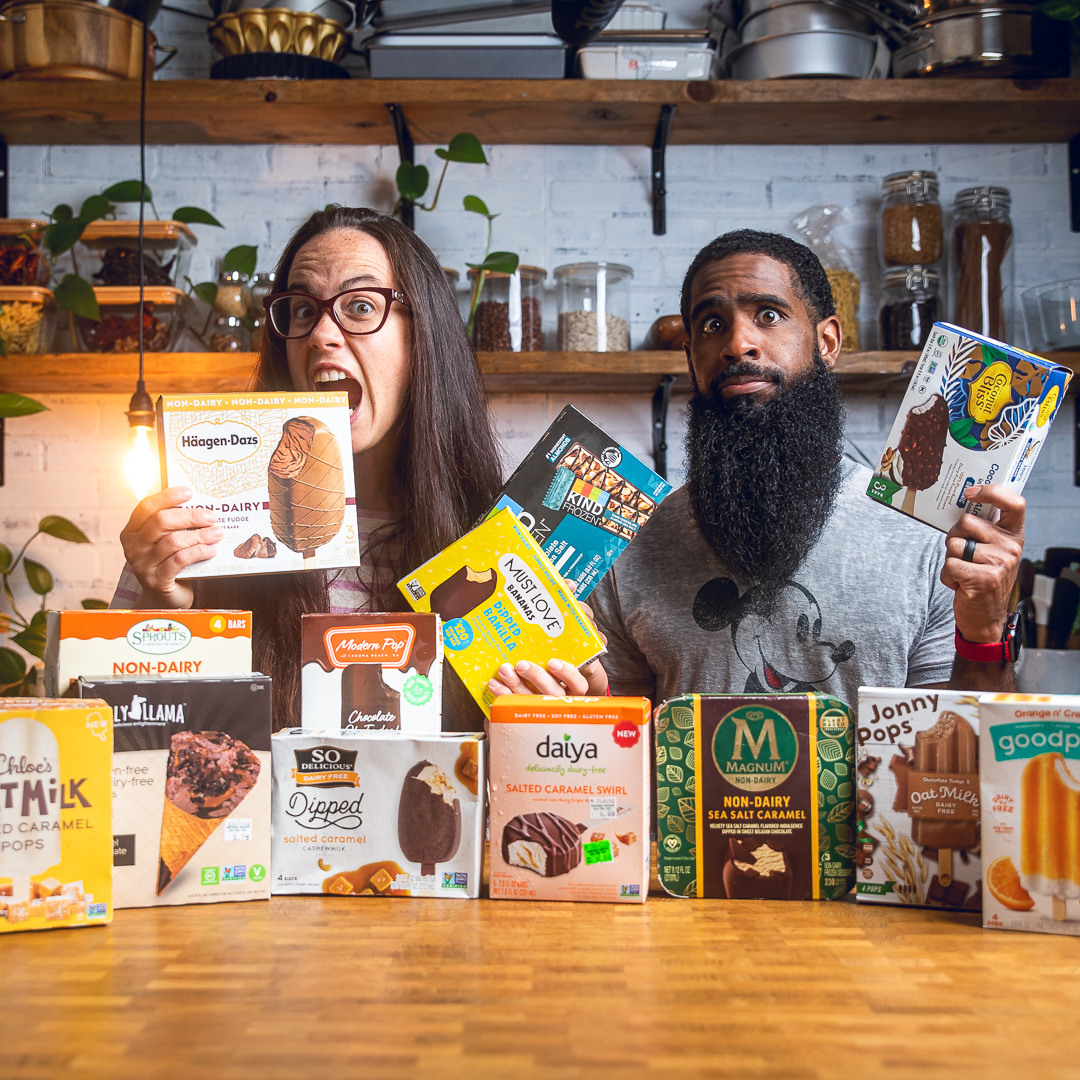 A couple behind an assortment of vegan ice cream bars packages.