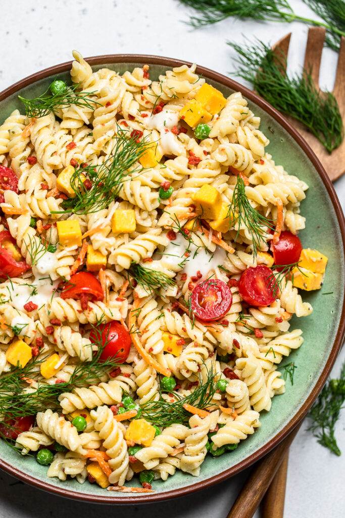 a serving bowl of vegan bacon ranch pasta salad with fresh ingredients.