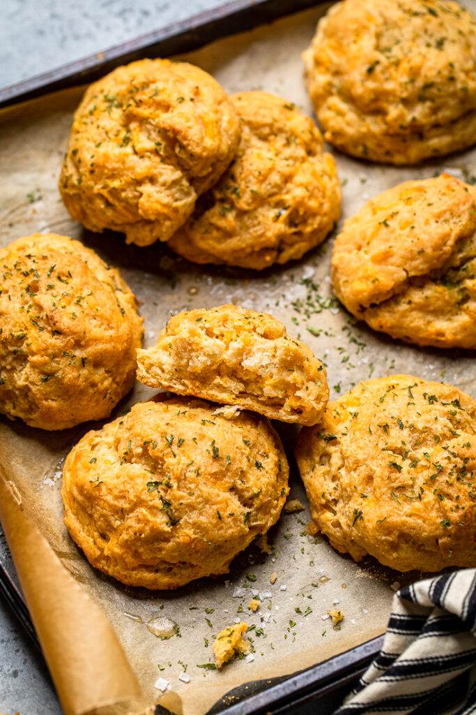 A sheet pan tray of vegan cheddar bay biscuits topped with fresh herbs. 