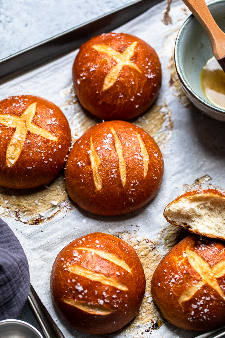 A tray of vegan pretzel buns that have different designs scored into the top.