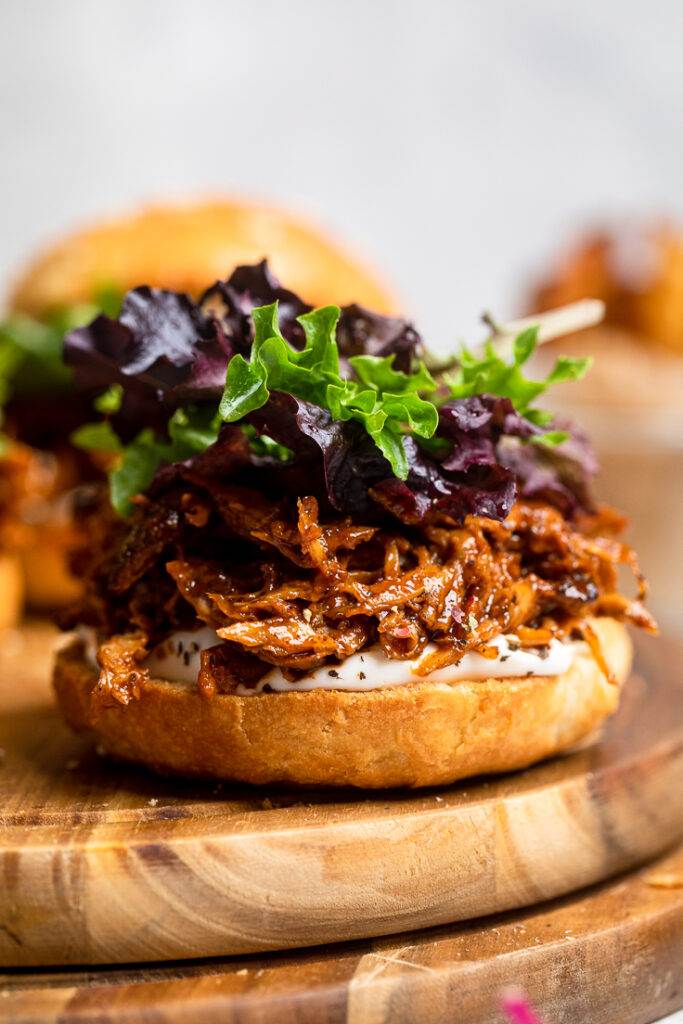 An open faced Vegan pulled chicken sandwich with purple and green lettuce on top. 