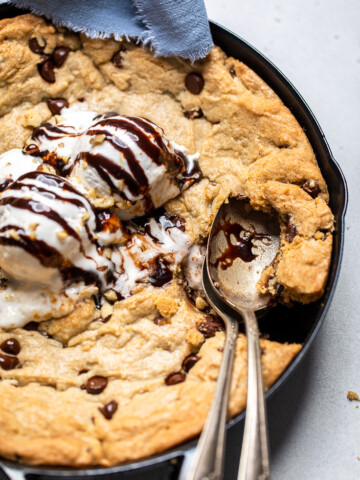 A vegan chocolate chip skillet cookie with chocolate drizzle and ice cream.