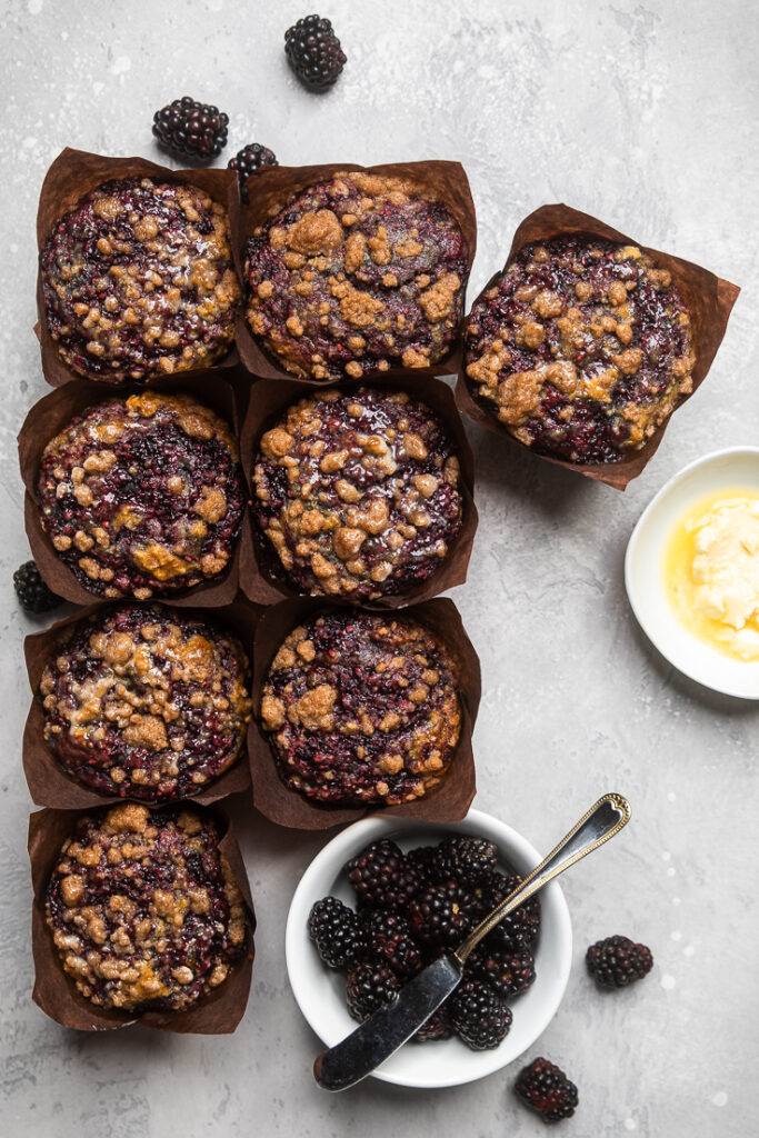 Eight Gluten free vegan blackberry cinnamon muffins arrange on a gray table.
