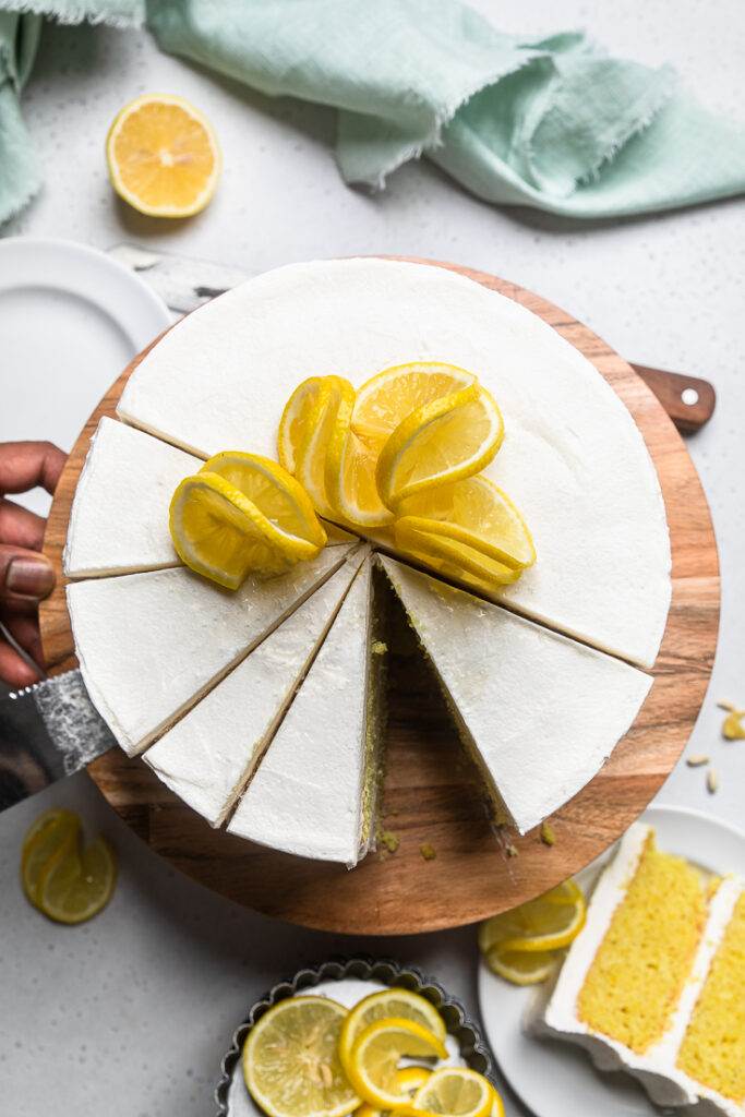 Top of a frosted layered Vegan Lemon Cake with half the cake cut into slices.