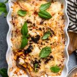 A scalloped white casserole dish filled with cooked vegan baked ziti.