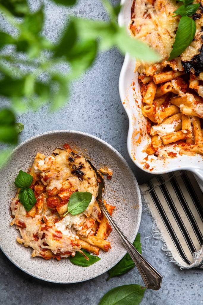 A bowl of vegan baked ziti topped with fresh basil. 