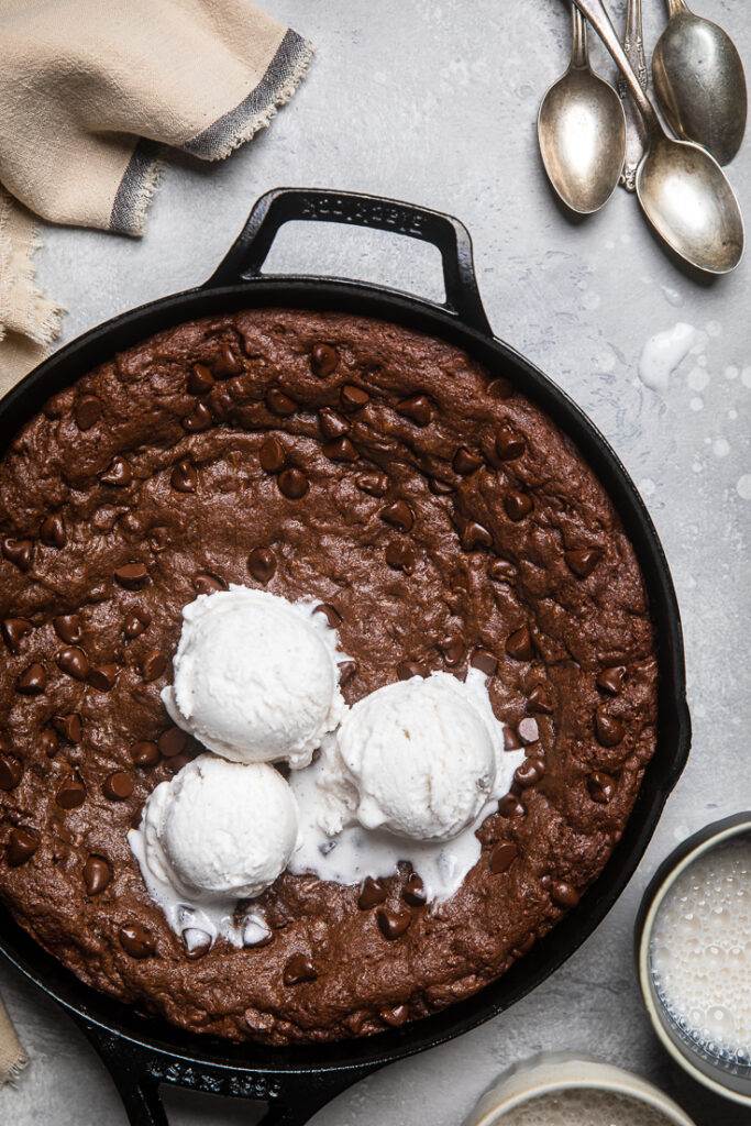 A Vegan double chocolate chip cookie skillet with vegan vanilla ice cream not yet cut.