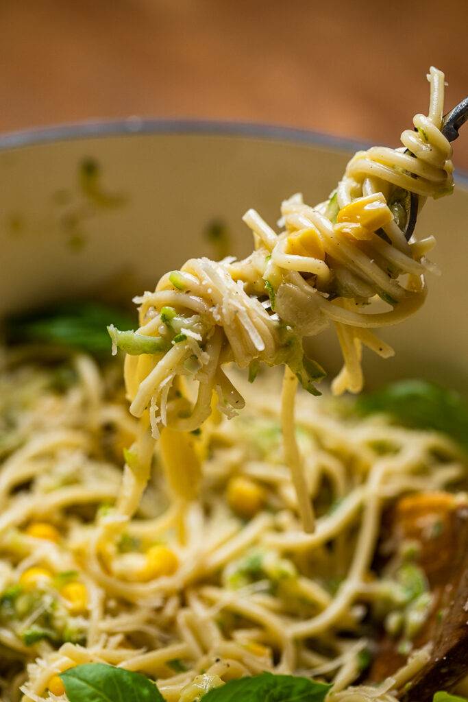 A forkful of creamy vegan zucchini and corn pasta.