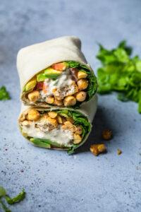 A Vegan chickpea caesar wrap cut in half and stacked on top of each other.