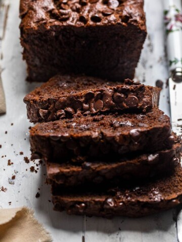 Slices of Vegan Chocolate Zucchini Bread on a white table.