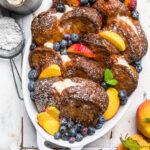 A casserole dish of Whipped Cream Cheese Vegan Stuffed French Toast with Peaches and Blueberries.