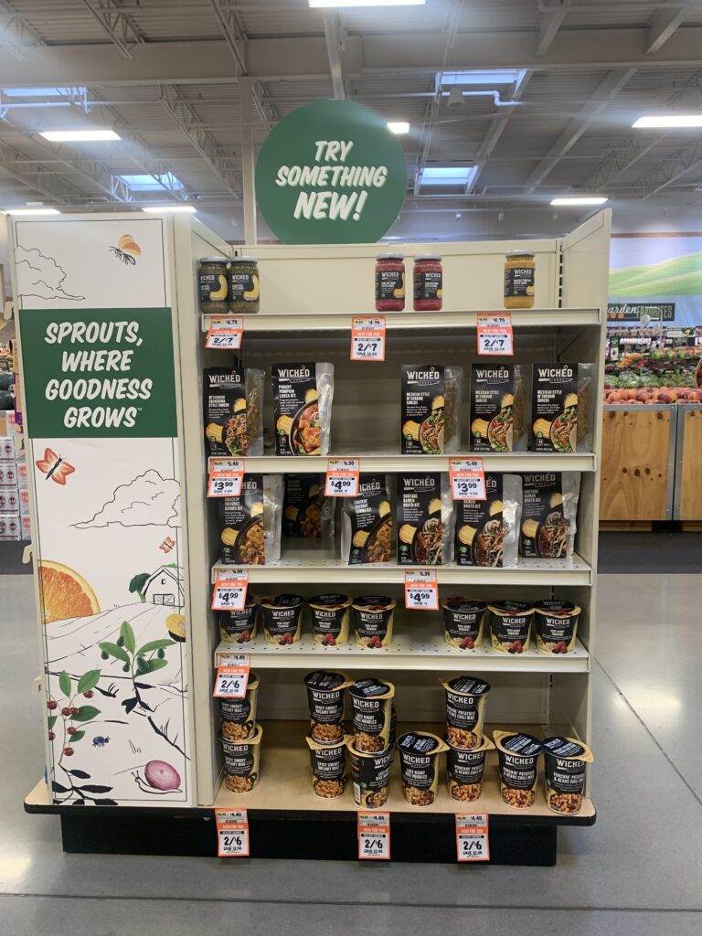 A display shelf of Wicked Kitchen plant-based foods inside Sprouts grocery store.