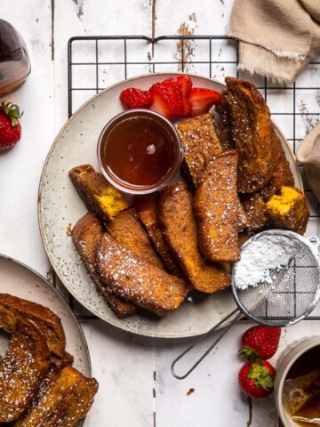Vegan French Toast Sticks on a ceramic plate with small bowl of syrup.