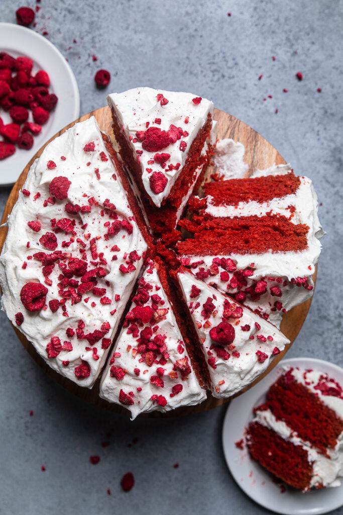 Top view of vegan red velvet cake sliced on a wooden cake stand. 