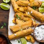 A plate of cheesy baked vegan taquitos arranged together.
