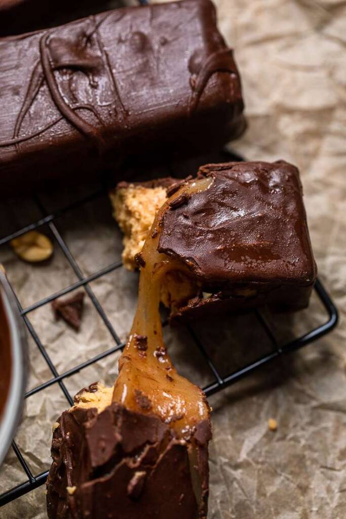 Gooey caramel being pulled from the center of a Vegan Snickers Bar. 