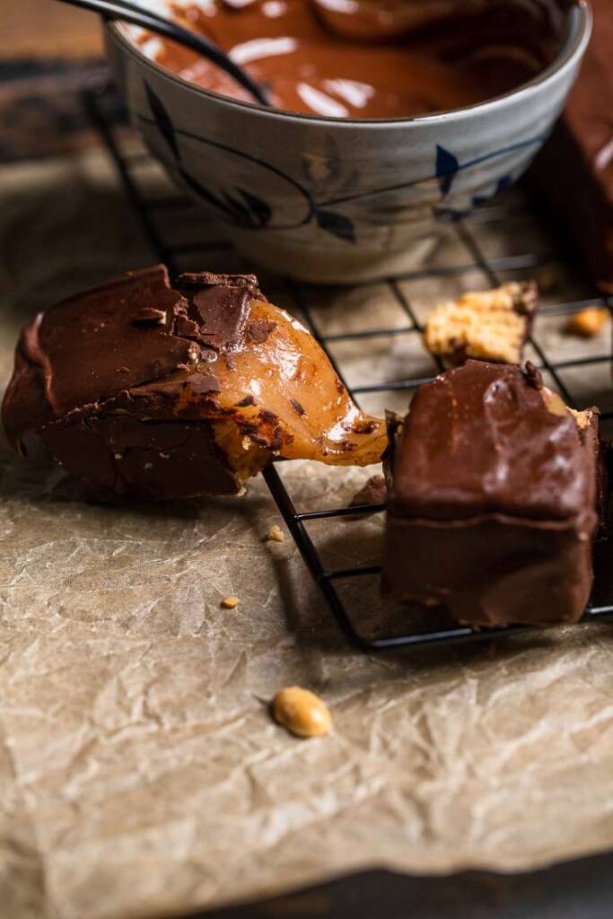 A Vegan Snickers Bar halved and gooey caramel being pulled from the center. 