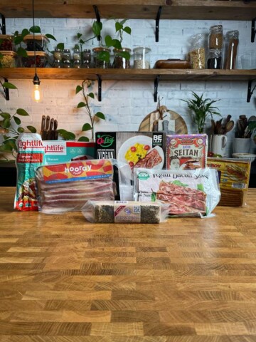 An assortment of vegan bacon product packages on a table.