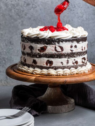 Lightly frosted vegan black forest cake with cherries on top.