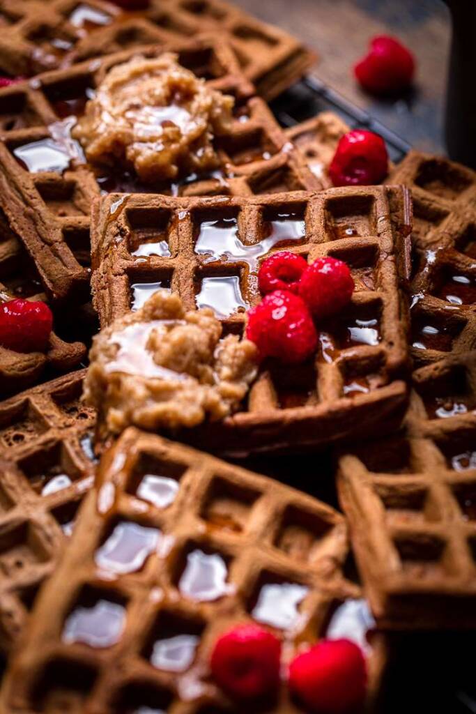 A vegan chocolate pumpkin waffle topped with cinnamon butter, fresh raspberries and syrup.