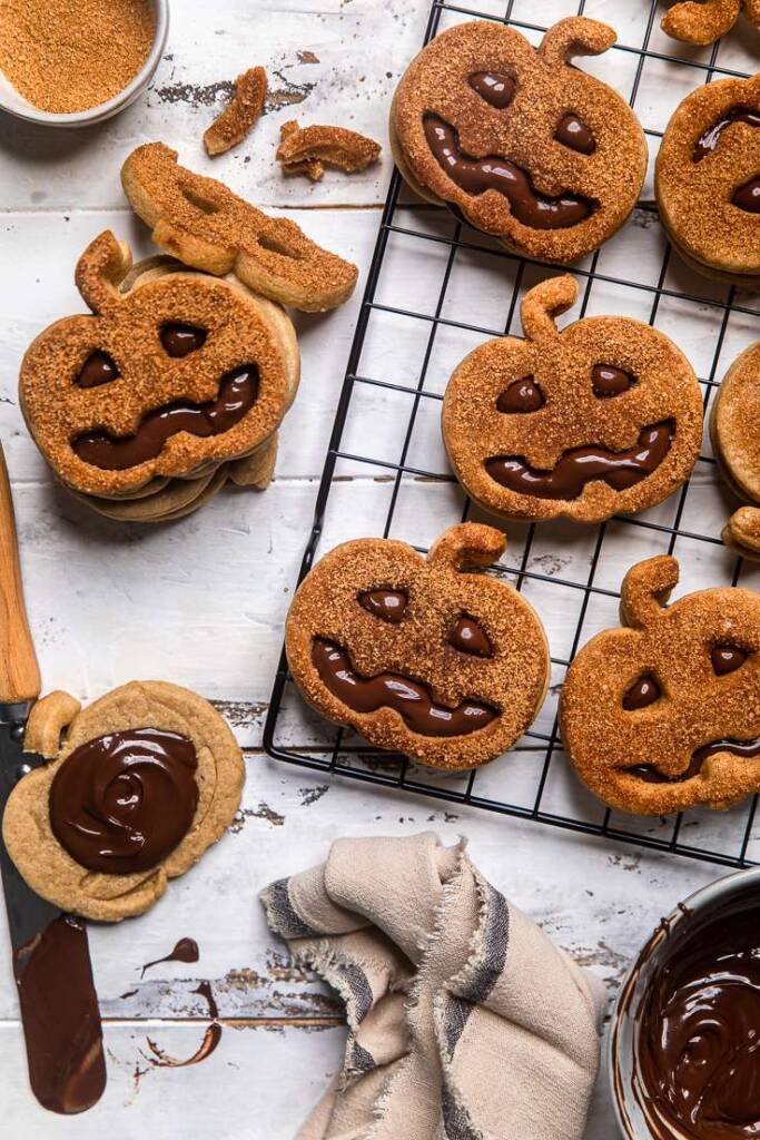 Vegan pumpkin sugar cookies with chocolate oozing out from the face cut outs. 