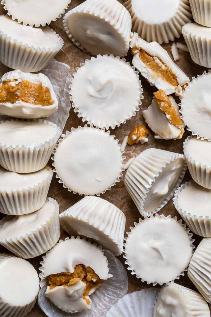 A bunch of vegan white chocolate peanut butter cups on a table.