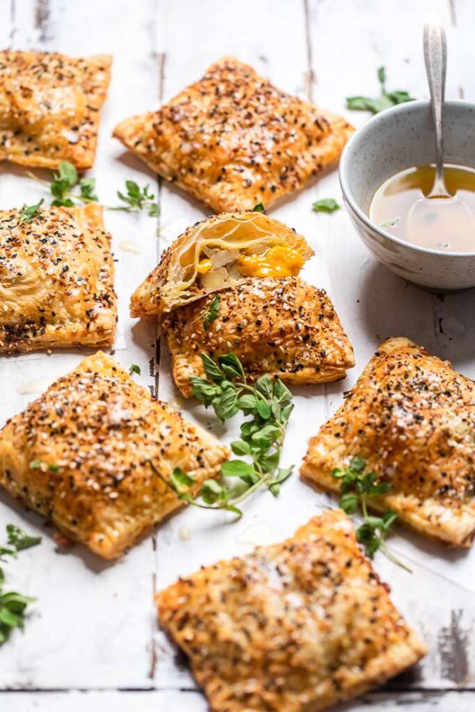 Several cheesy vegan potato and onion puff pastries with glaze on the side. 