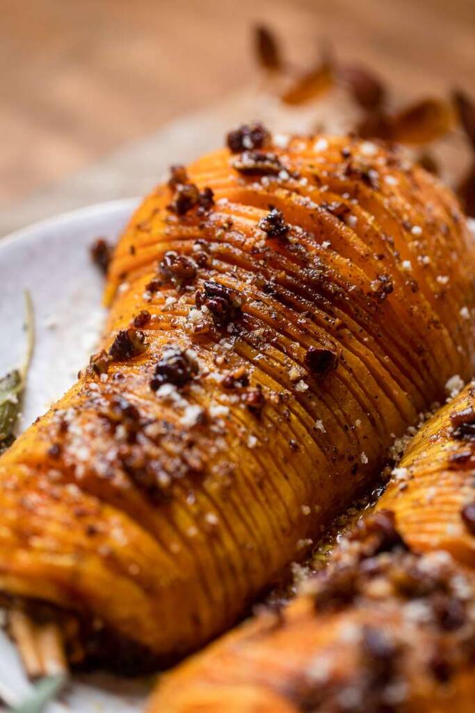 Vegan Hasselback squash sliced and cooked on a white plate. 