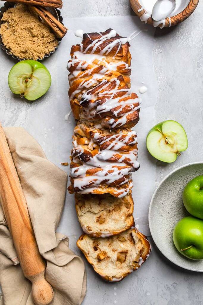 Vegan apple pull apart bread on a gray table with freshly halved green apples. 