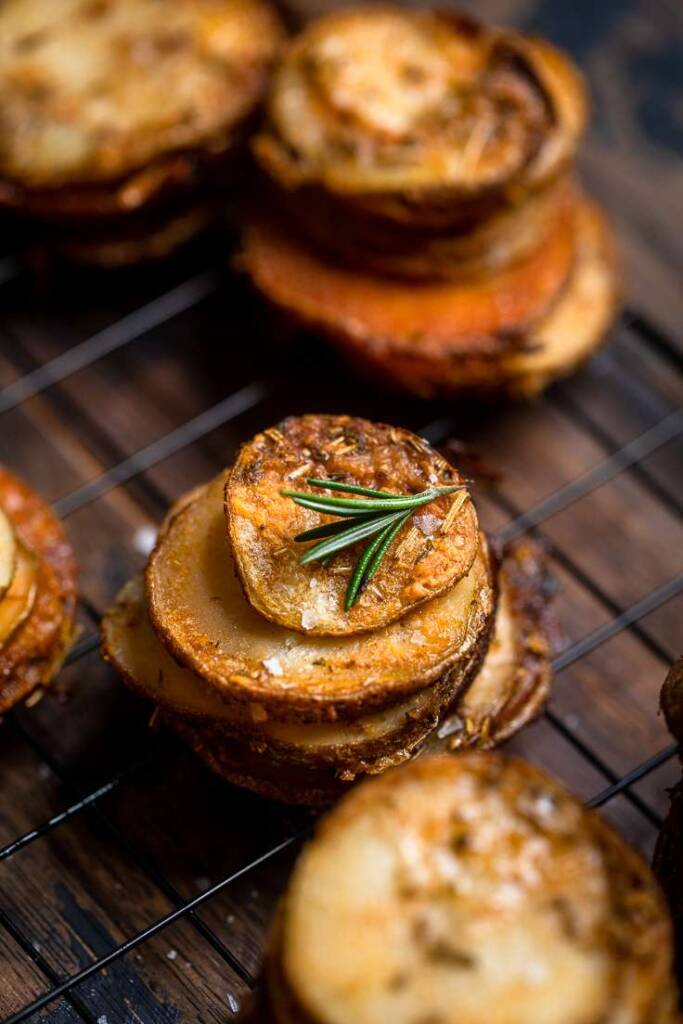 Crispy cheesy and Herb vegan potato stacks on a wire rack with fresh rosemary.