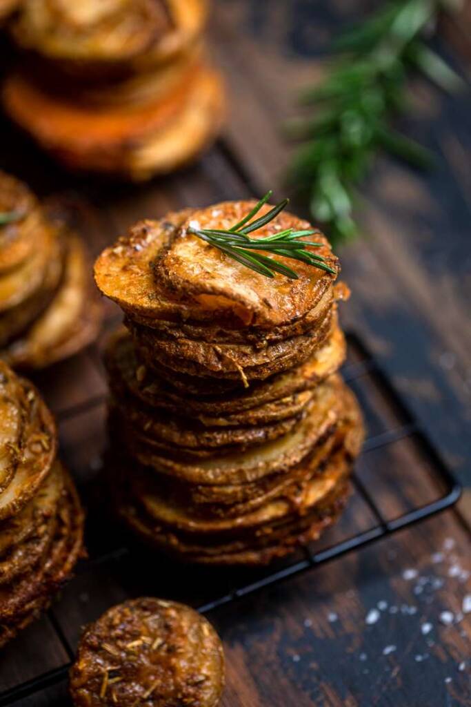 A single Crispy cheesy and Herb vegan potato stack topped with fresh rosemary. 