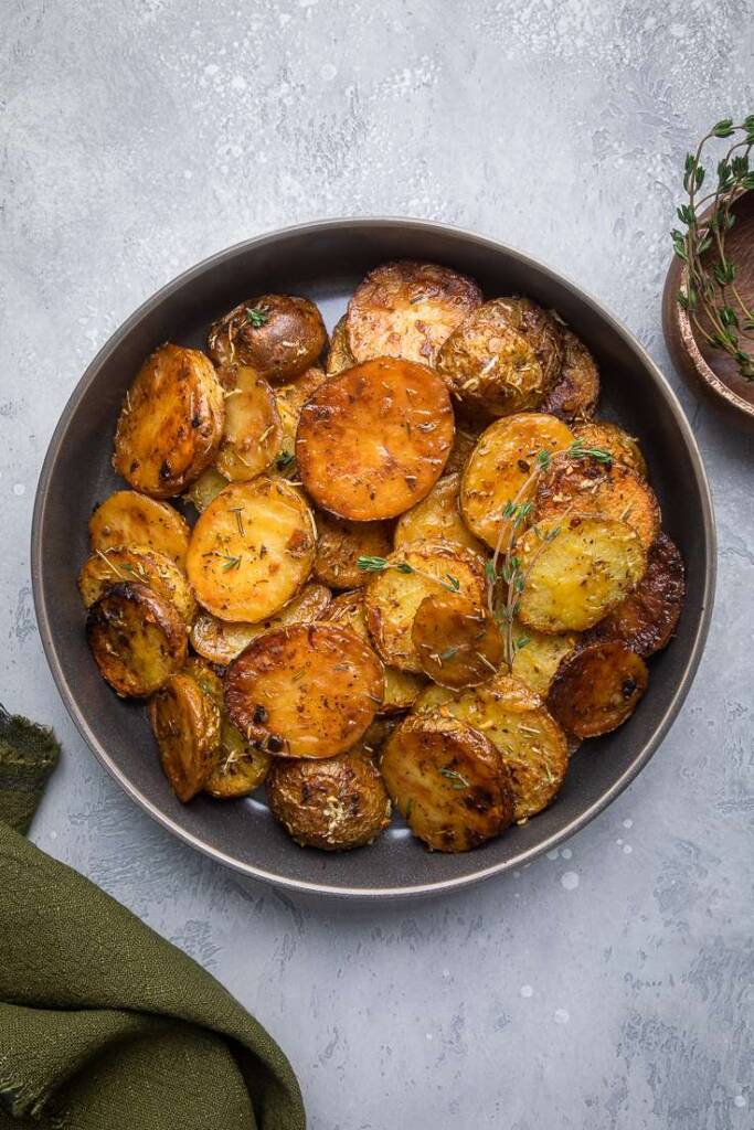 Saucy crispy lemon rosemary butter melting potatoes in a bowl on a gray table. 