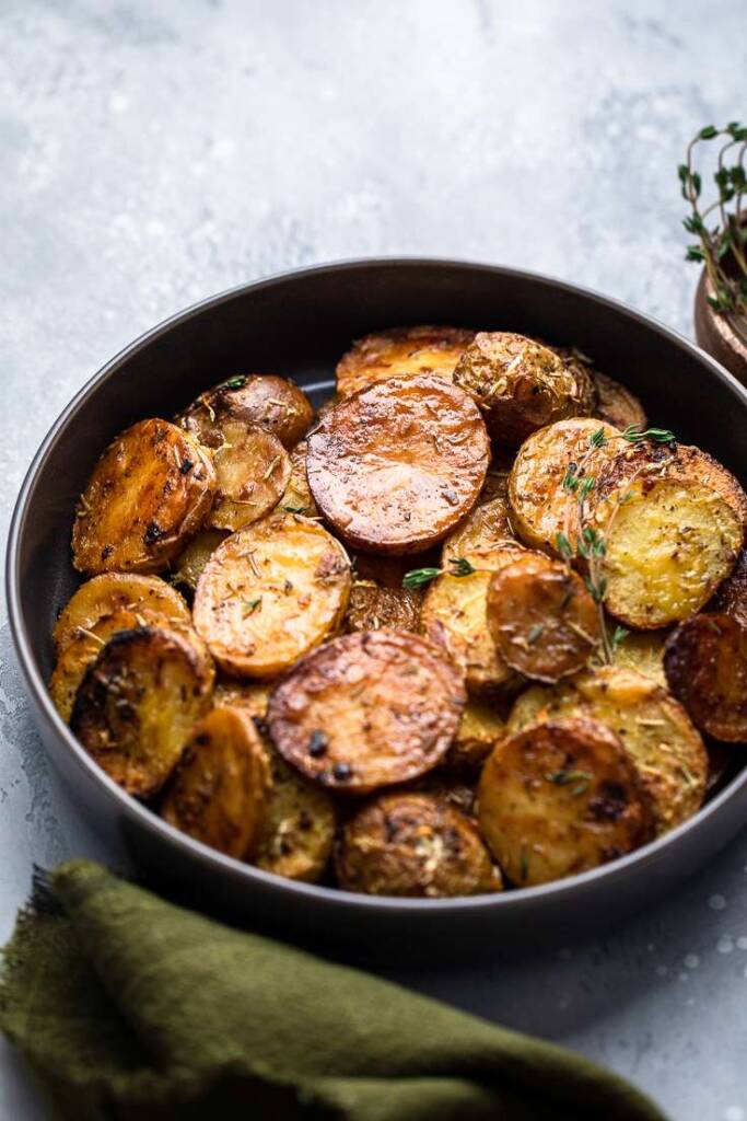 a serving bowl of crispy lemon rosemary butter melting potatoes brushed with sauce. 