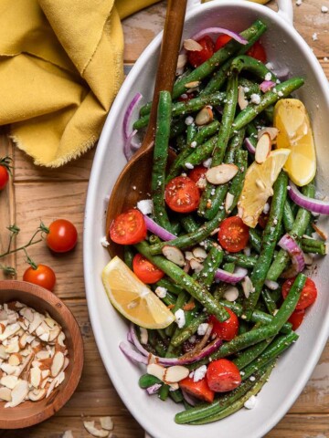 A serving dish of vegan green bean salad with feta and almonds.