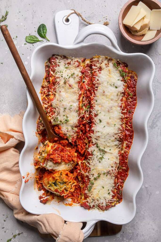 A serving dish of cheesy vegan lasagna roll-ups. 