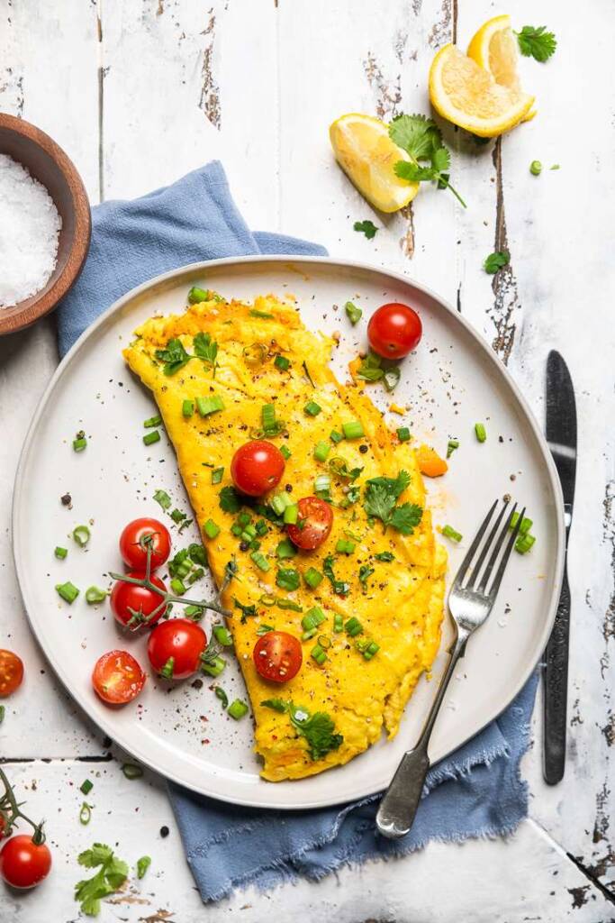 Just Egg Omelet on a plate with fresh tomatoes and green onions. 