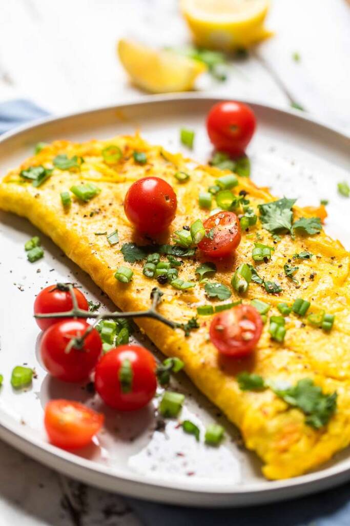 A vegan omelette with cherry tomatoes and green onions on a plate. 