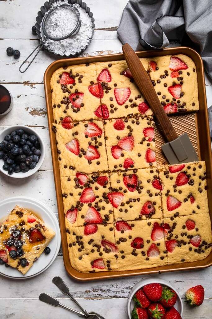 a gold baking sheet of vegan Sheet pan pancakes with strawberries and chocolate chips. 