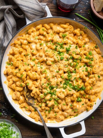 A white pot of 15 minutes easy vegan buffalo mac and cheese with green onions.