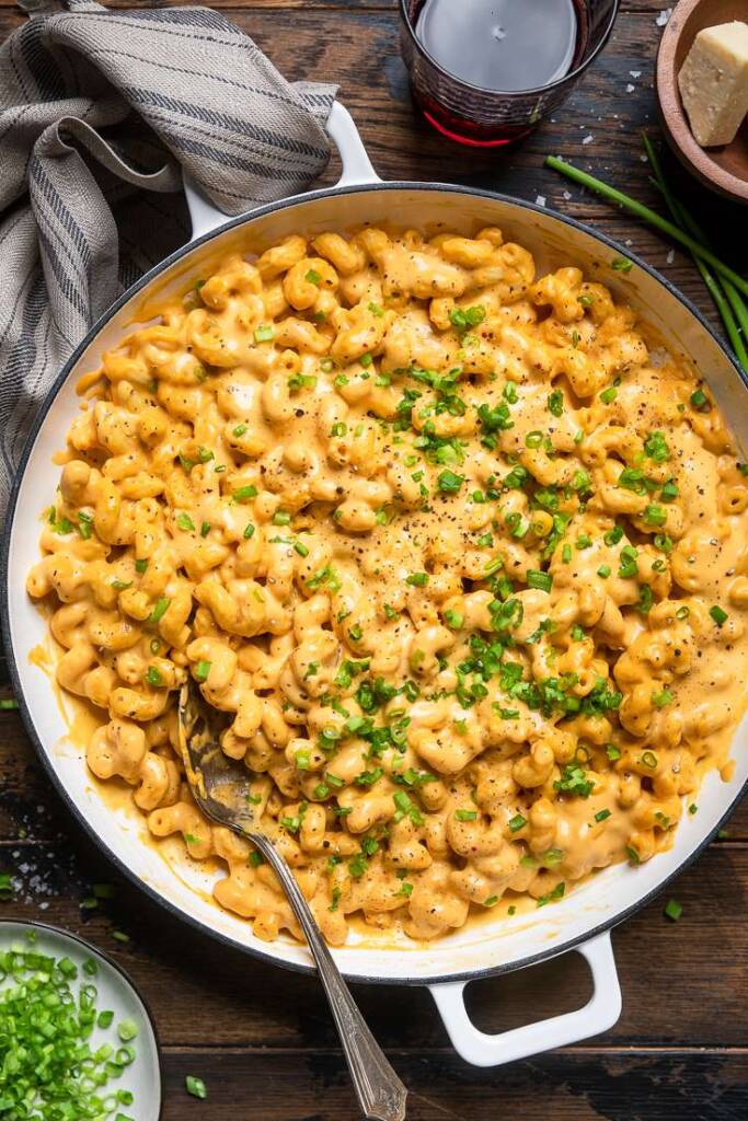 A large pot of easy vegan buffalo mac and cheese with black pepper and green onoins.