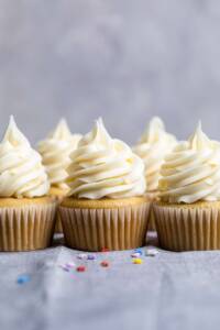 A few vegan vanilla cupcakes with spiraled vegan vanilla frosting on top.