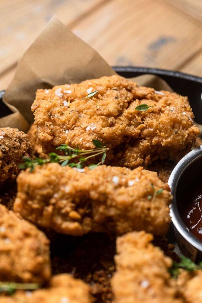 A few pieces of vegan fried chicken topped with flakey salt and fresh thyme. 