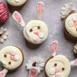 An assortment of Vegan bunny cupcakes on a gray board with white flowers.
