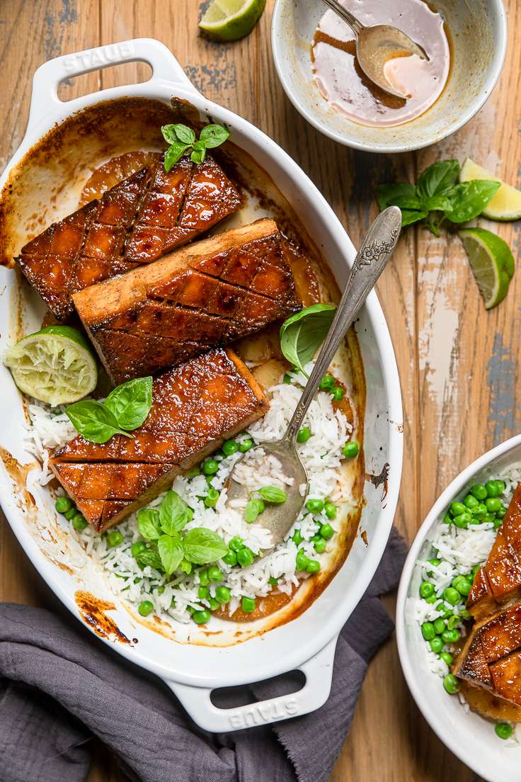 brown sugar glazed tofu in a white casserole dish with white rice and peas on the side.