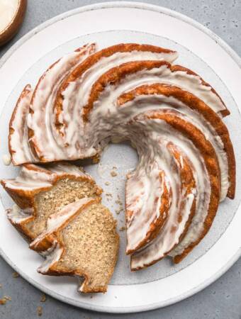 Vegan banana bundt cake with thick icing on top and two slices cut
