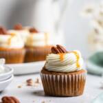 A vegan carrot cake cupcake with vegan cream cheese frosting and caramel drizzle.