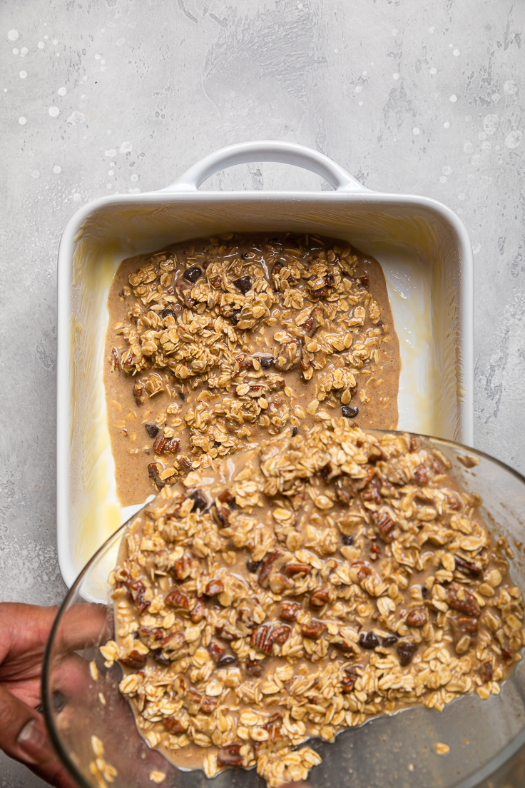 Pouring mixed vegan banana bread baked oatmeal ingredients into a casserole dish.