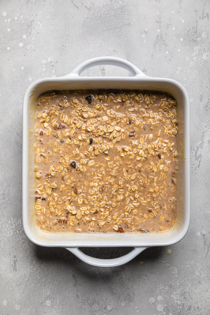 A casserole dish with vegan banana bread baked oatmeal ingredients spread out evenly.