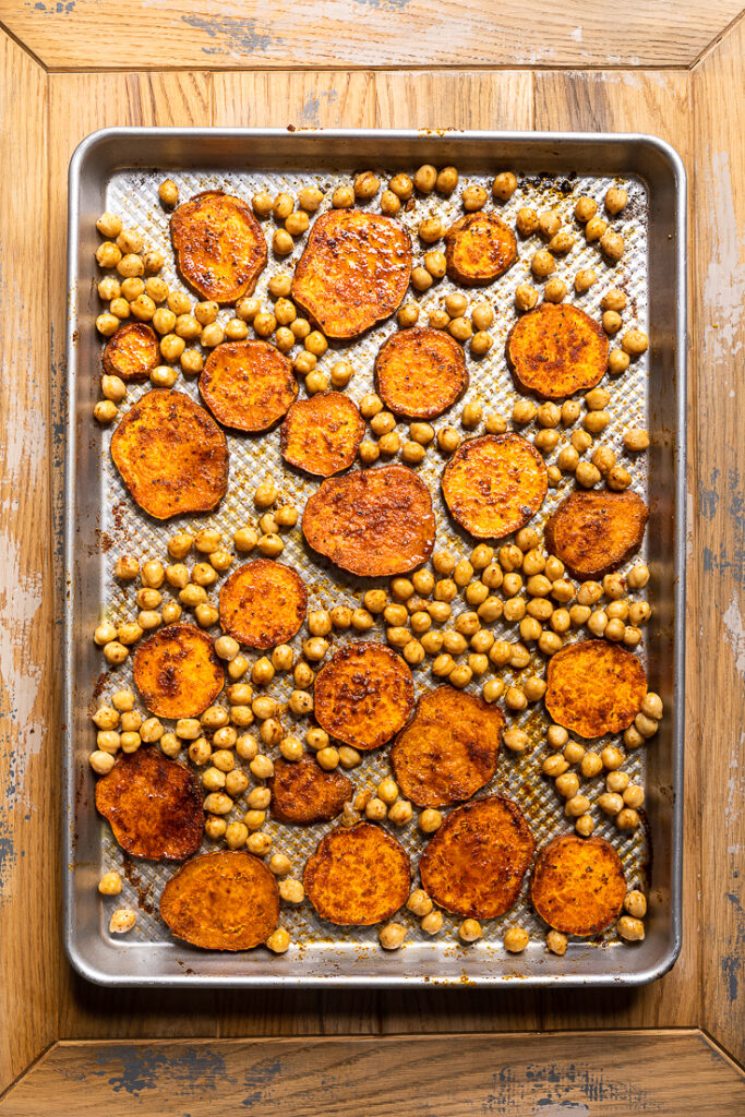 A sheet pan with cooked sliced sweet potatoes and chickpeas. 