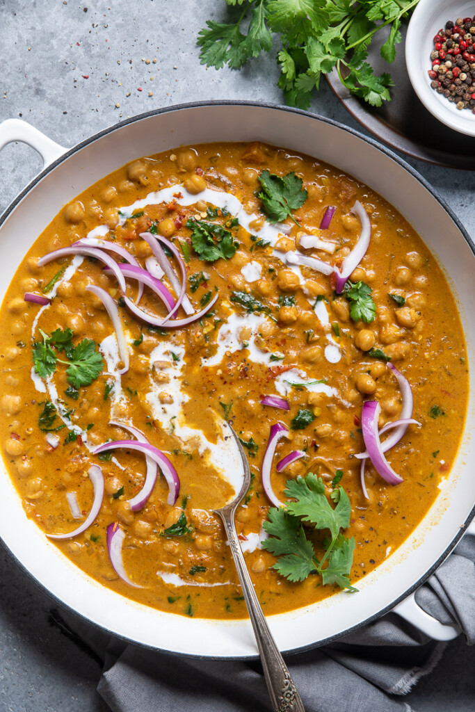 A bowl of vegan chickpea curry with red onions, coconut milk and herbs. 